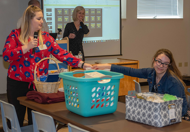 South Hills DMS 2019 class representative Lesley Hogan, left, holds the basket while DMS second-year class representative Robyn Pheasant draws the willing ticket for the 2019 basket raffle. DMS Program Director, Tricia Turner, watches in the background.