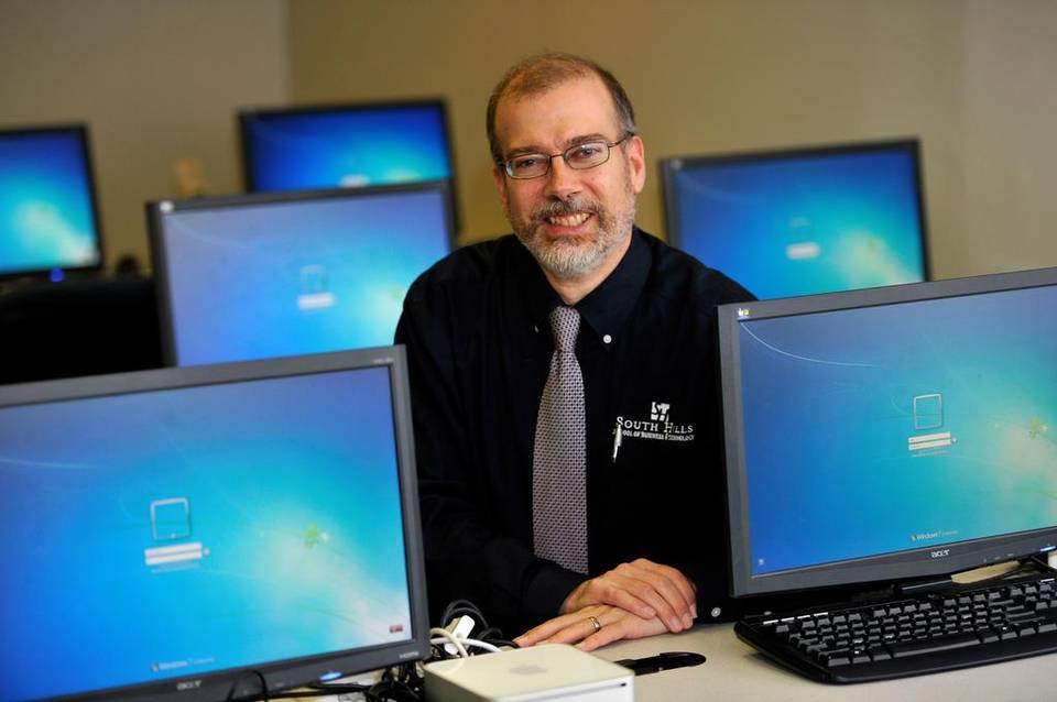 This photo shows a male sitting around computers