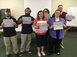 This photo shows a group of students smiling holding certificates