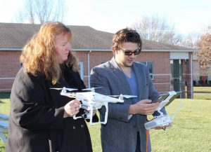 Two people operate a drone.